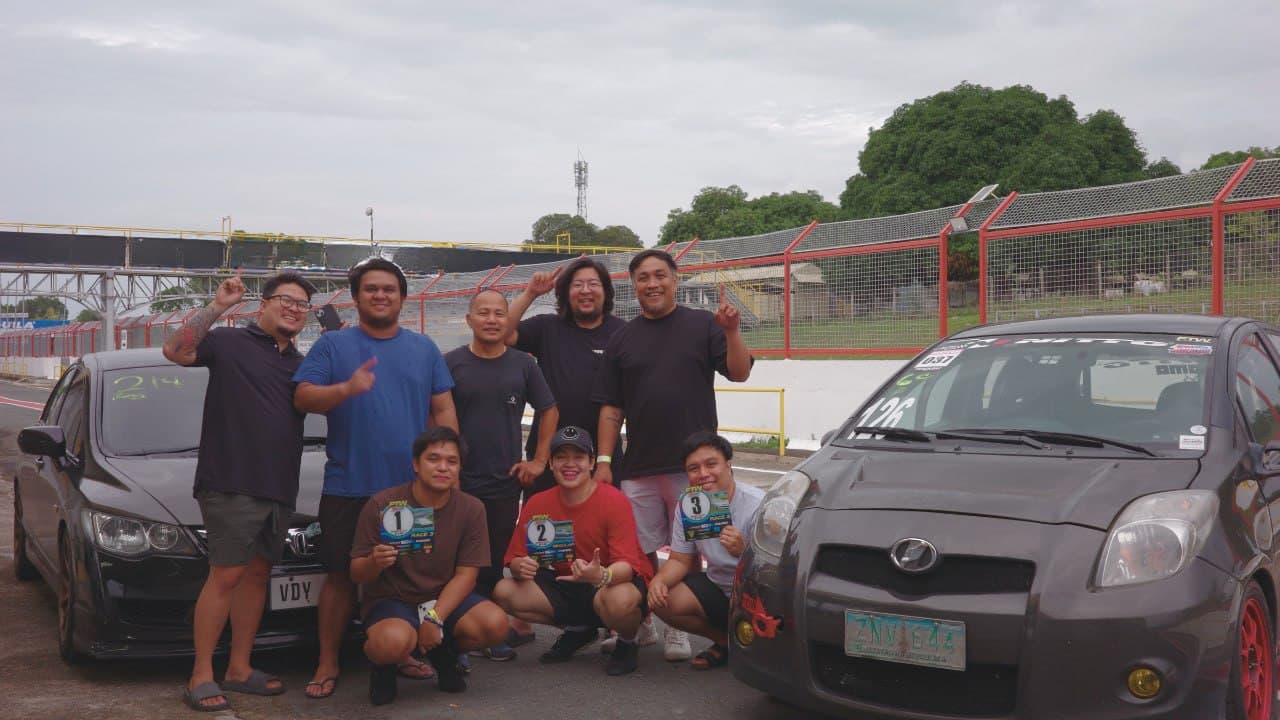 DLC Automotive community members with two cars at a racetrack