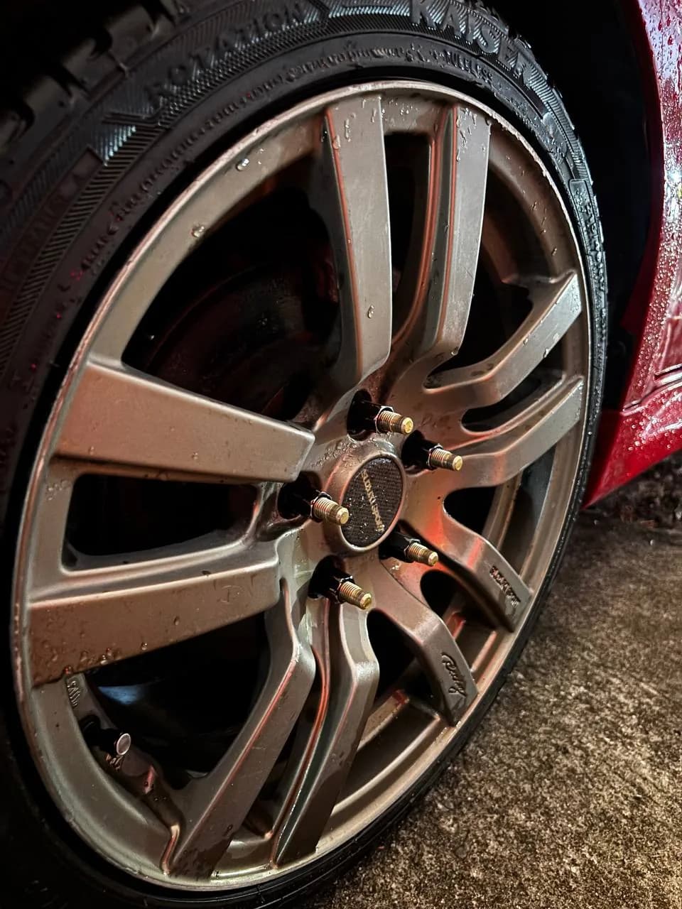 Extended wheel studs visible through black open-ended lug nuts on an installed wheel